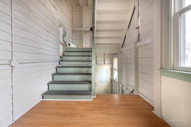 staircase with hardwood / wood-style flooring, lofted ceiling, and wood walls