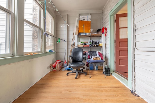 office space with light wood-type flooring, wooden walls, and ornamental molding