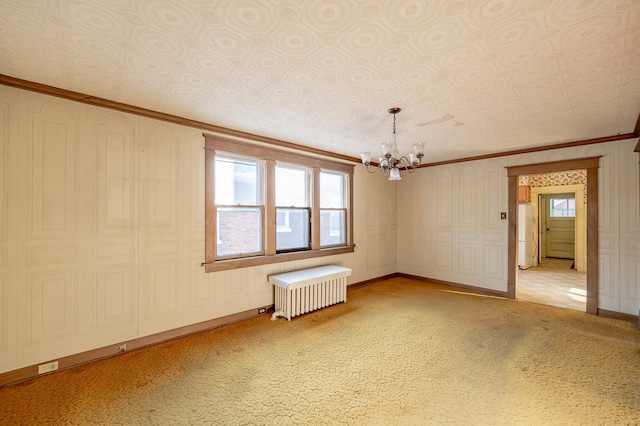 carpeted spare room with radiator heating unit, crown molding, and an inviting chandelier