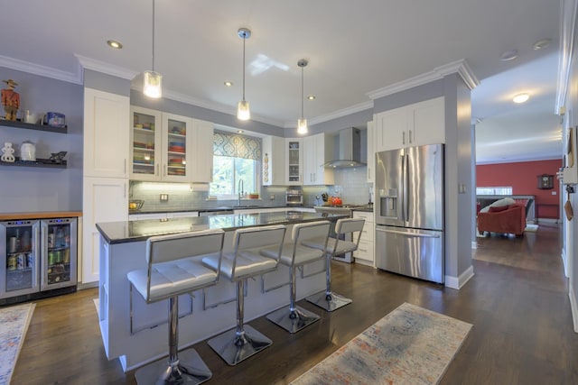 kitchen with wall chimney range hood, white cabinets, stainless steel fridge with ice dispenser, a center island, and wine cooler