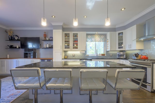 kitchen featuring a center island, hanging light fixtures, stainless steel stove, a kitchen bar, and white cabinetry