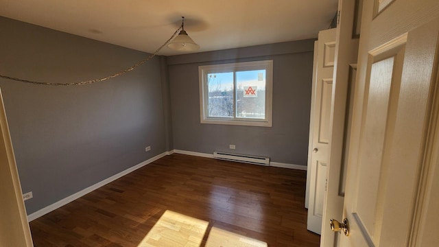 spare room with dark wood-type flooring and a baseboard radiator