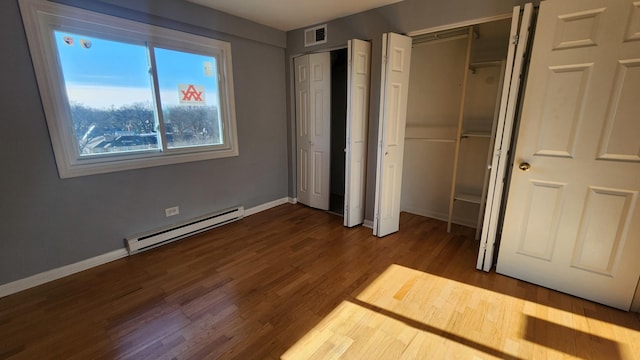 unfurnished bedroom with dark hardwood / wood-style flooring and a baseboard heating unit