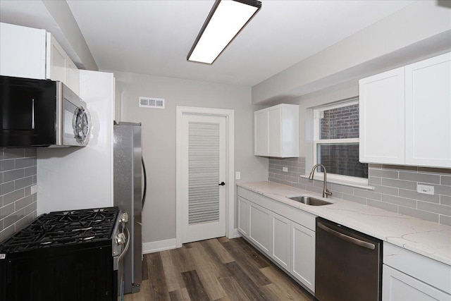 kitchen with white cabinets, sink, appliances with stainless steel finishes, tasteful backsplash, and light stone counters