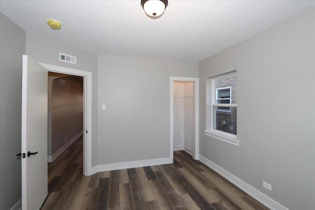 unfurnished bedroom featuring a walk in closet, dark hardwood / wood-style floors, and a closet