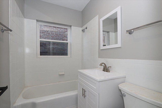 full bathroom with vanity, toilet, tile walls, and tiled shower / bath combo