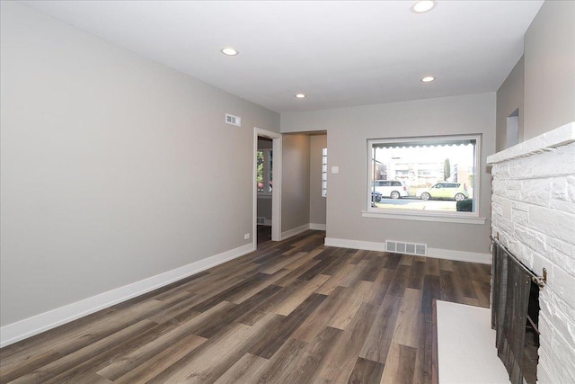 unfurnished living room featuring dark hardwood / wood-style floors and a stone fireplace