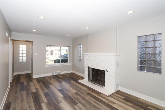 unfurnished living room featuring a fireplace and dark wood-type flooring