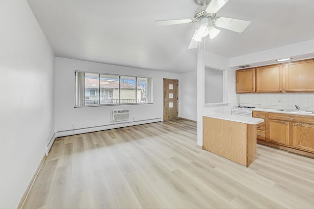 kitchen with ceiling fan, sink, a baseboard radiator, light hardwood / wood-style flooring, and backsplash