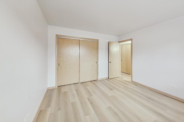 unfurnished bedroom featuring light wood-type flooring and a closet