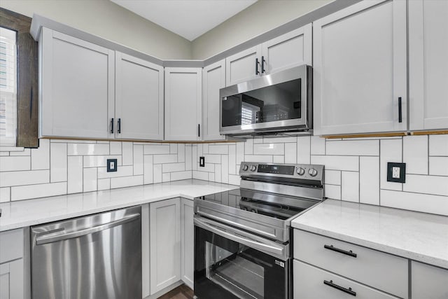 kitchen featuring backsplash, light stone countertops, and appliances with stainless steel finishes