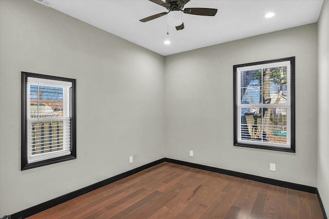 empty room featuring plenty of natural light, dark wood-type flooring, and ceiling fan