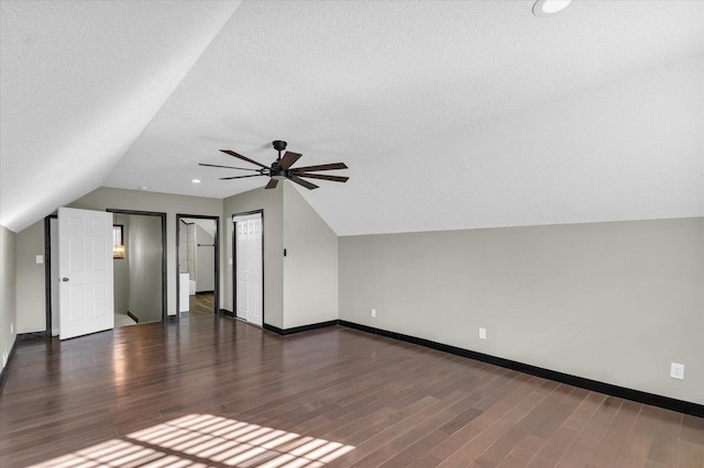 additional living space featuring ceiling fan, dark hardwood / wood-style floors, lofted ceiling, and a textured ceiling