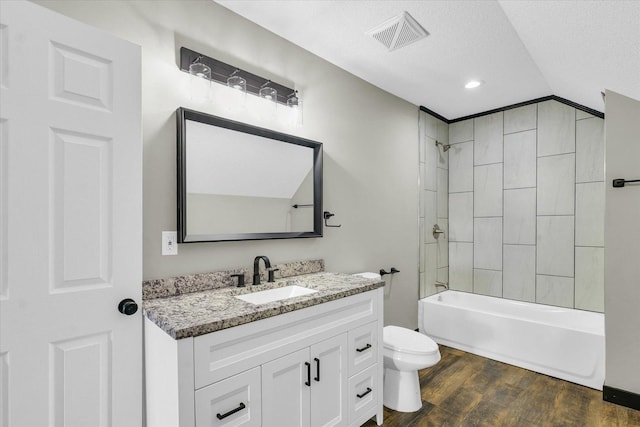 full bathroom with vanity, tiled shower / bath combo, toilet, a textured ceiling, and wood-type flooring