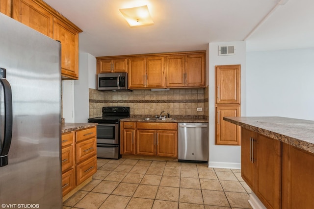 kitchen with backsplash, light tile patterned flooring, sink, and stainless steel appliances