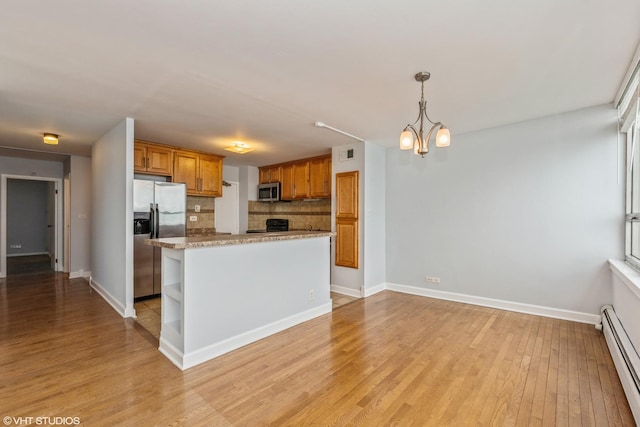 kitchen featuring an inviting chandelier, a baseboard heating unit, pendant lighting, decorative backsplash, and appliances with stainless steel finishes