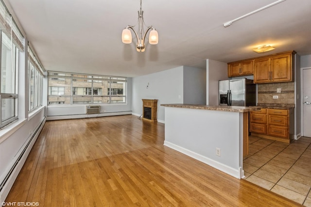 kitchen featuring pendant lighting, decorative backsplash, stainless steel fridge, a baseboard radiator, and a chandelier