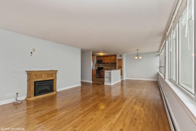 unfurnished living room with a baseboard radiator, light hardwood / wood-style flooring, and a notable chandelier