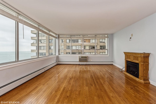 interior space with hardwood / wood-style floors, a water view, a wall mounted air conditioner, and a baseboard heating unit