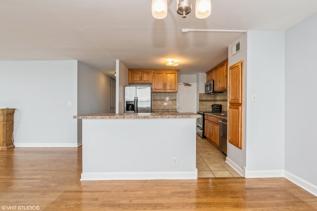 kitchen featuring a center island, stainless steel appliances, tasteful backsplash, light hardwood / wood-style flooring, and decorative light fixtures