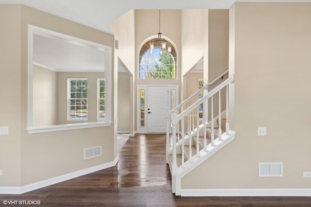 entrance foyer with a towering ceiling, dark hardwood / wood-style floors, and an inviting chandelier