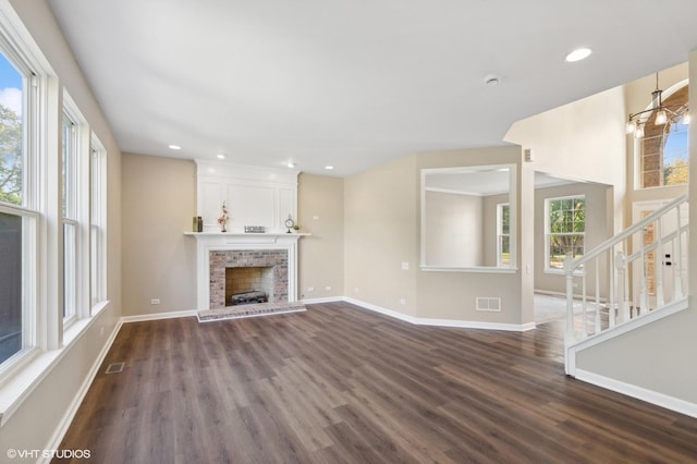 unfurnished living room with a chandelier, dark hardwood / wood-style floors, and a brick fireplace