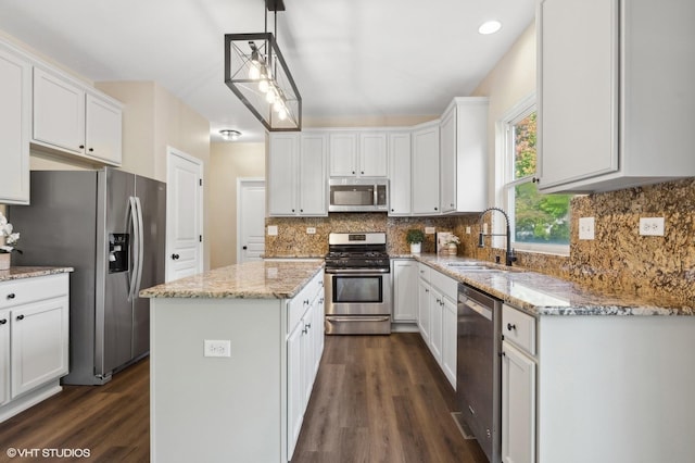 kitchen featuring appliances with stainless steel finishes, sink, decorative light fixtures, white cabinets, and a center island