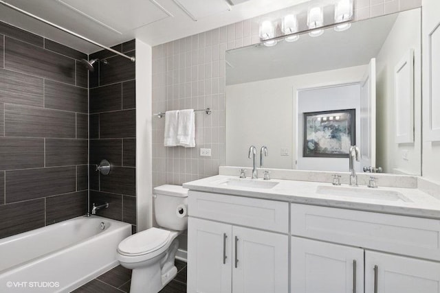 full bathroom featuring tiled shower / bath, vanity, toilet, and tile walls