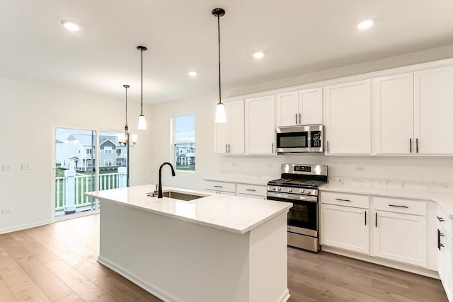 kitchen with stainless steel appliances, sink, decorative light fixtures, a center island with sink, and white cabinets