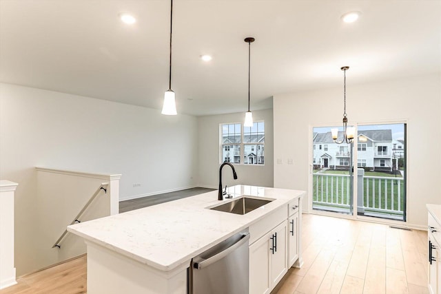 kitchen featuring dishwasher, sink, hanging light fixtures, and an island with sink