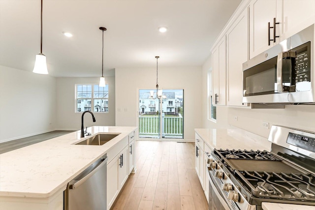 kitchen featuring stainless steel appliances, white cabinetry, a kitchen island with sink, and sink