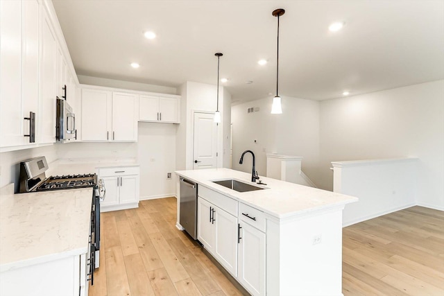 kitchen featuring white cabinetry, sink, decorative light fixtures, a kitchen island with sink, and appliances with stainless steel finishes