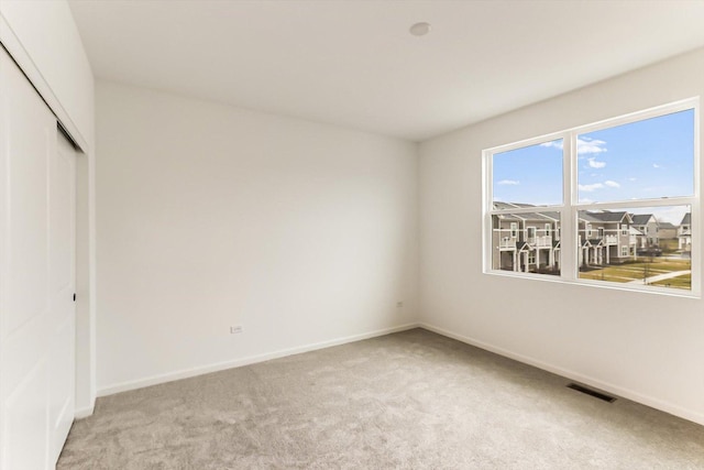 unfurnished bedroom featuring light colored carpet and a closet