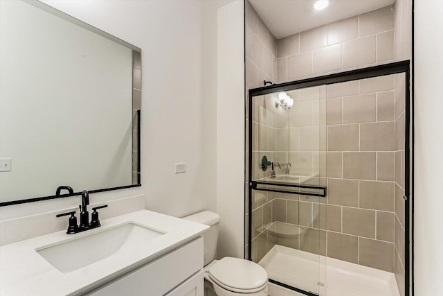 bathroom with a shower with door, vanity, and toilet