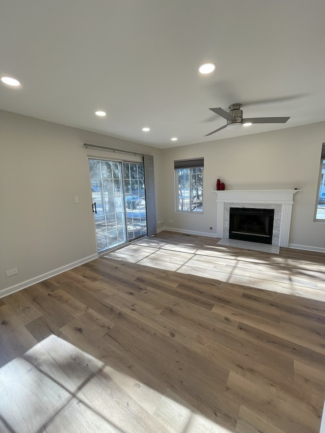 unfurnished living room with ceiling fan, a fireplace, and wood-type flooring