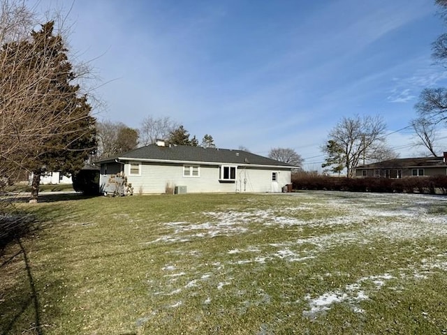 rear view of property with central air condition unit and a lawn