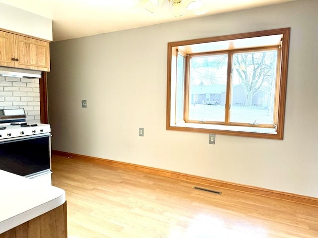 kitchen with decorative backsplash, white stove, exhaust hood, and light hardwood / wood-style flooring