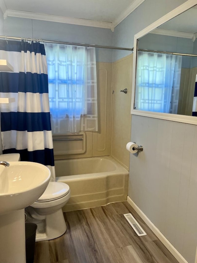 bathroom with crown molding, hardwood / wood-style floors, shower / bath combo, and toilet