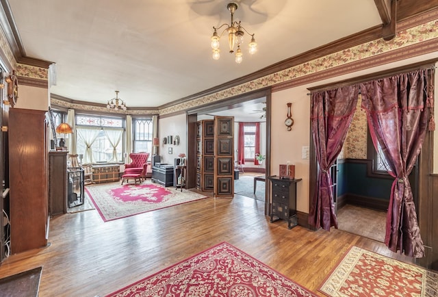 interior space featuring wood finished floors, crown molding, baseboards, and an inviting chandelier