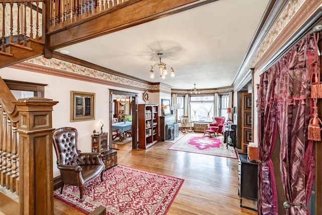 interior space with ornamental molding, wood finished floors, a chandelier, and stairway
