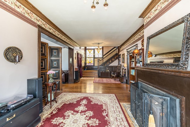 sitting room with stairway, a notable chandelier, wood finished floors, and crown molding