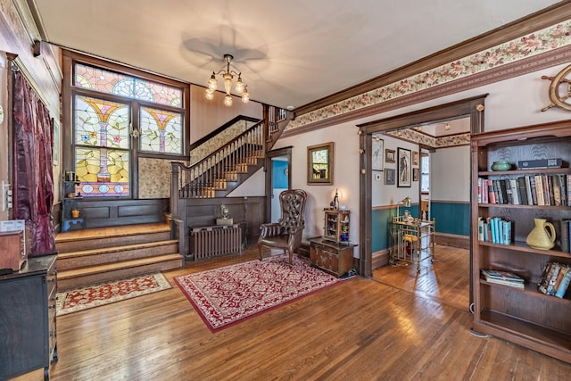 living area with stairs, crown molding, baseboards, a chandelier, and hardwood / wood-style flooring