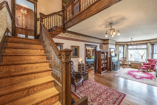 interior space with an inviting chandelier, crown molding, and wood finished floors