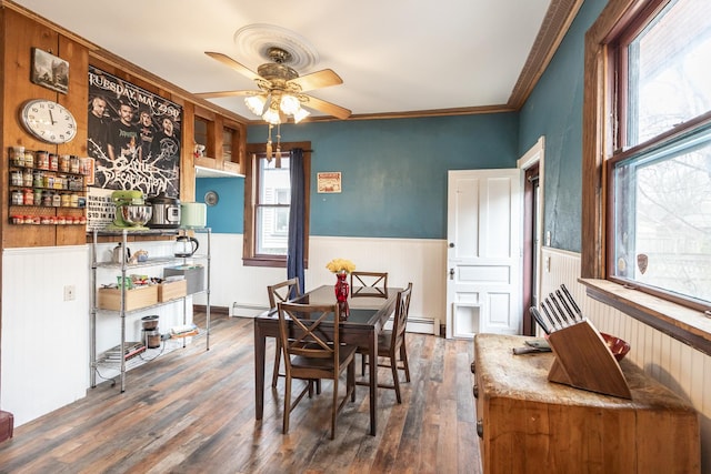 dining area featuring wainscoting, baseboard heating, wood finished floors, ceiling fan, and crown molding