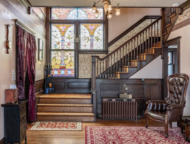 foyer featuring radiator heating unit, wood finished floors, and stairs