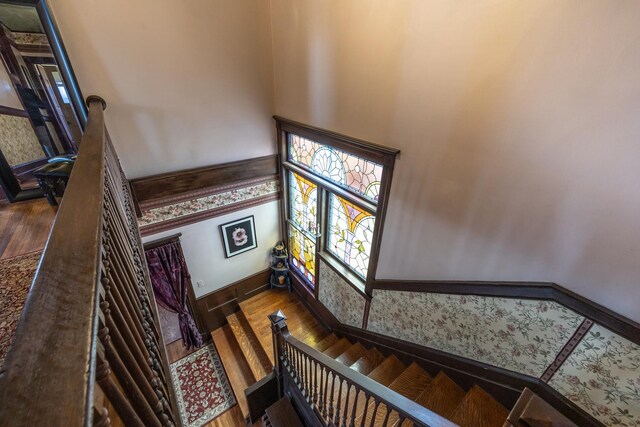 stairway featuring wainscoting, baseboards, wood finished floors, and wallpapered walls