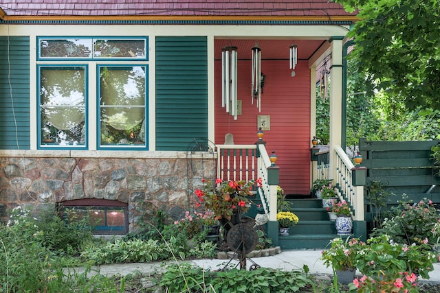 view of exterior entry with stone siding and covered porch