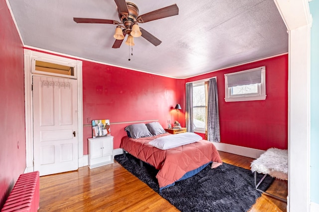 bedroom featuring baseboards, a ceiling fan, wood finished floors, and a textured ceiling
