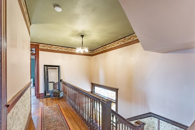 hallway with an inviting chandelier, wood finished floors, and an upstairs landing