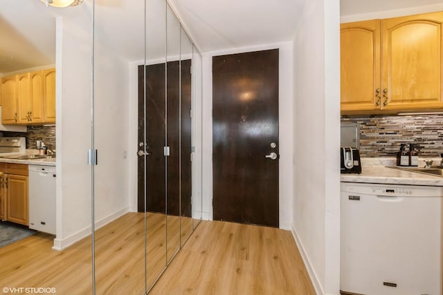 kitchen with decorative backsplash, light hardwood / wood-style flooring, and white dishwasher